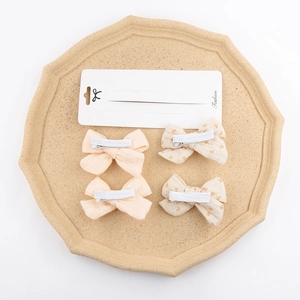 4-pack fabric bow hair clips with pink and floral patterns on a stone display tray