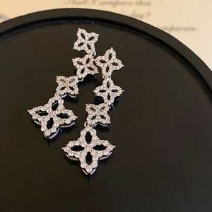 Detailed view of silver four-leaf clover drop earrings with micro-set cubic zirconia crystals