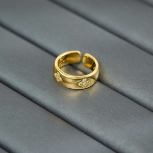 Macro shot of gold four-leaf clover ring with sparkling zircon stones and open band design