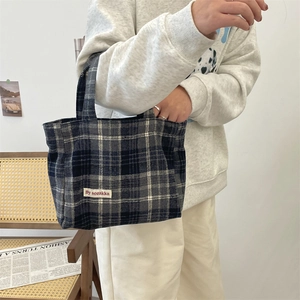 Detail shot of the vintage plaid canvas tote bag worn on the arm in a warm studio