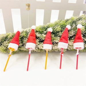 Mini Christmas lollipop hats set of five on white surface with snowy pine tree background