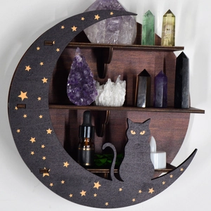 Detail of moon-shaped wooden crystal shelf with black cat silhouette and gold stars