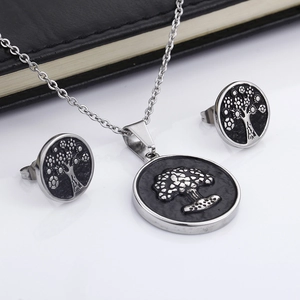 Silver Tree of Life necklace and stud earrings set with black base on a notebook