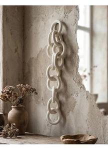 Detail of minimalist white ceramic interlinked rings hanging on a textured wall