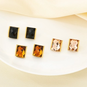 Close-up of square glass earrings in black, amber, and champagne with 18K gold plating