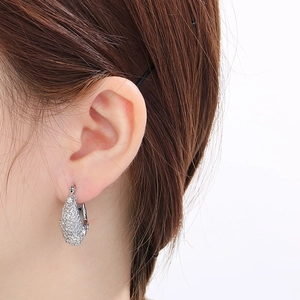 Détail de la boucle d'oreille en U argentée en forme de goutte avec motif ajouré et diamants