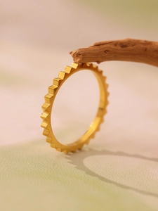 Detail shot of golden gear-shaped stainless steel ring on natural wooden branch
