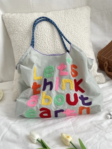 Close-up of chenille embroidery let's think about earth on a gray canvas tote bag