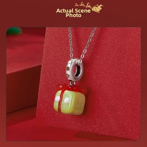 Detail of S925 silver Christmas gift box pendant with green enamel and red accents