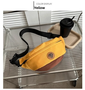 Detail of yellow and brown Oxford cloth chest bag with logo patch on a display cart