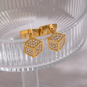 Macro view of gold-plated square cufflinks with sparkling cubic zirconia on glass edge