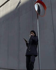 Urban street shot of black loose-fit hoodie and joggers set against a grey wall