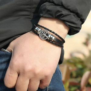 Close-up of men's multilayer braided leather bracelet with silver tree of life charm