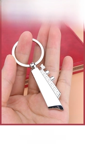 Detail view of a silver cruise ship keychain with a multi-functional bottle opener feature