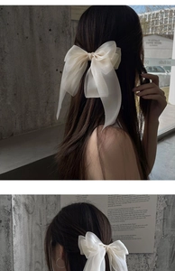 Elegant beige bow hair clip styled on a model's ponytail for a sophisticated back view