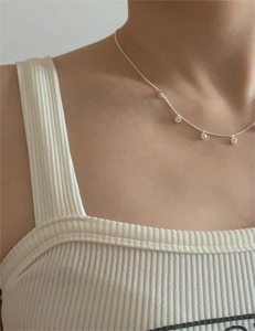 Close-up of minimalist 925 silver necklace with round zircon pendants on neck