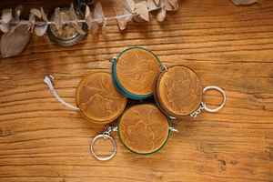 Macro detail of four leather tape measures with embossed floral patterns on wood