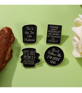 Set of four black and gold enamel pins with humorous slogans for bags and clothes