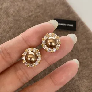 Detailed shot of vintage gold pearl earrings with zircon halo on dark fabric