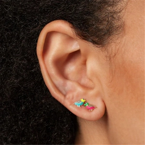 Close-up of bird-shaped colorful enamel earrings worn by a model with dark curly hair