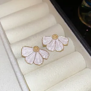 Boucles d'oreilles fleurs blanches au centre doré dans un coffret à bijoux