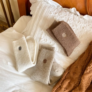 Detailed view of three pairs of thick knit winter socks with small floral embroidery details