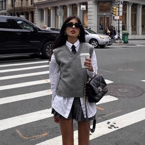 Street style view of grey V-neck knitted vest paired with white shirt and pleated skirt