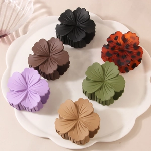 Set of six colorful matte flower hair claws on a decorative white ceramic tray