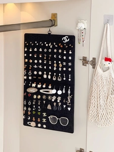 Detail of black felt organizer hanging in wardrobe with earrings and eyewear