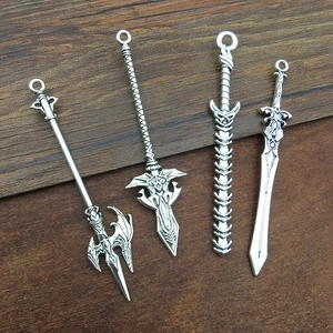 Detail of four antique silver alloy sword pendants on dark wood texture background