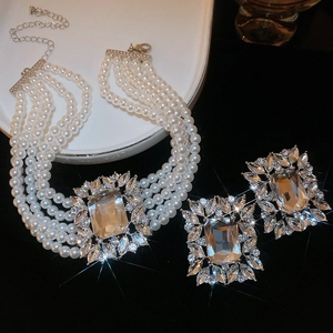 Close-up of luxury pearl necklace and earrings set with emerald-cut crystals