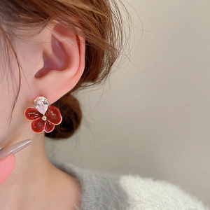 Détail de boucles d'oreilles fleur en émail rouge vintage avec zircon poire chic