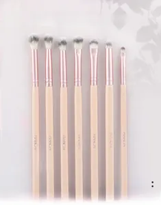 Détail de sept pinceaux de maquillage pour les yeux pêche avec viroles or rose sur rose