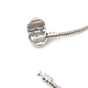 Macro shot of silver snake chain bracelet featuring a functional heart-shaped clasp detail