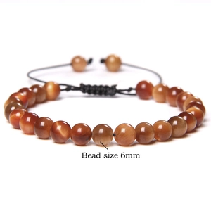 Detailed close-up of 6mm tiger eye beads and adjustable black woven cord on the bracelet