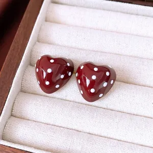 Red polka dot heart stud earrings in a wooden jewelry box with soft plush lining