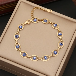 Close-up of golden stainless steel bracelet with blue heart-shaped enamel evil eyes