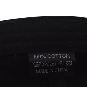 Gros plan détaillé de l'étiquette de lavage 100% coton sur une casquette noire