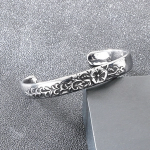Close-up of vintage engraved floral and vine patterns on retro silver titanium steel cuff