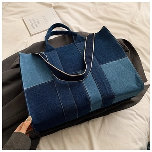 Detail view of denim patchwork tote bag with contrast stitching on white linen background