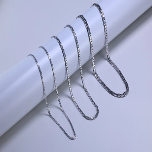Detail view of five sterling silver sailor chains hanging on a minimalist white display