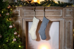 Close-up of cream and grey knitted Christmas stockings hanging on a wooden fireplace