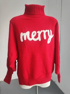 Detailed view of red turtleneck sweater with white merry embossed text and knit texture