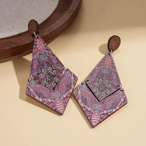 Detailed view of bohemian geometric wood earrings with colorful tribal pattern prints