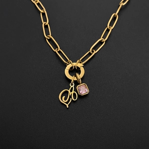 Detail of gold paperclip chain necklace with script letter B and pink gemstone pendant