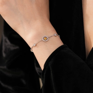 Detail of silver compass bracelet with yellow zircon on a black velvet background