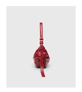 Detail view of red glossy leather shoulder bag showing pleated texture and strap