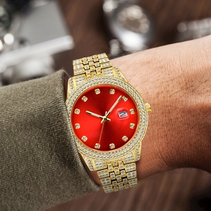 Close-up of men's gold diamond watch with red dial worn on wrist showing crystal details