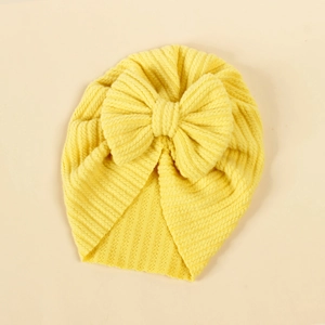 Detail der Baby Turban Mütze in leuchtendem Gelb mit großer Schleifenverzierung