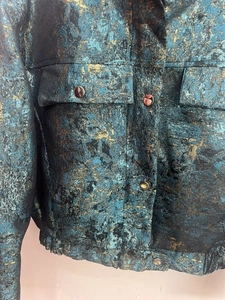 Close-up of metallic blue and gold jacquard fabric with detailed metal buttons on the pocket